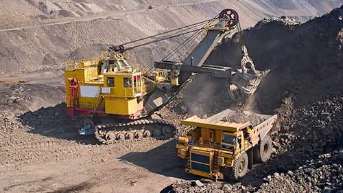 Heavy construction and mining equipment moving large dirt pile